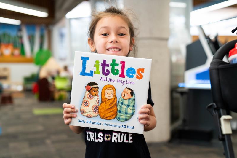 Girl with the book "Littles And How They Grow" that she will read
